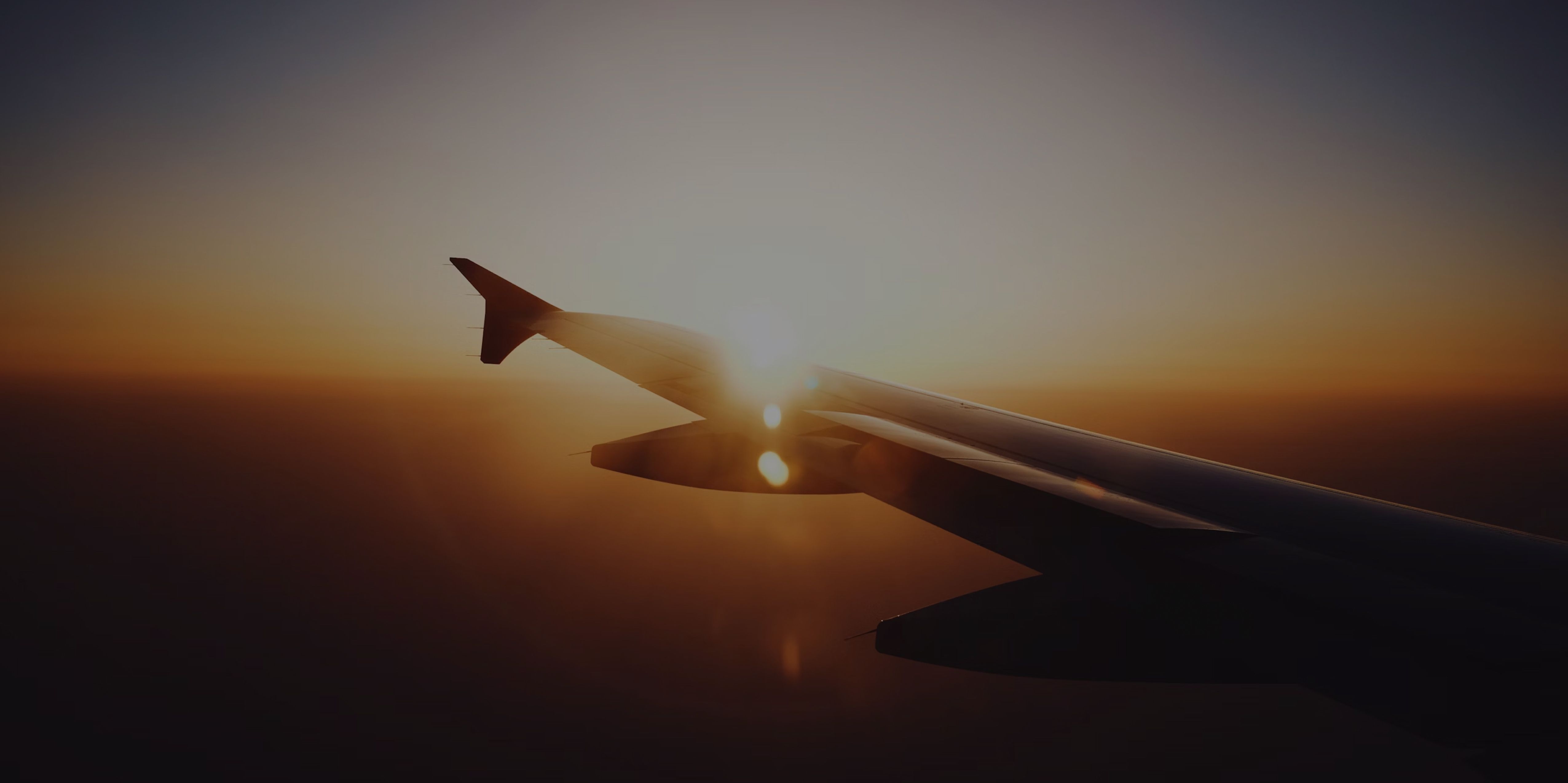 View of airplane wing against a glowing sunset sky during flight