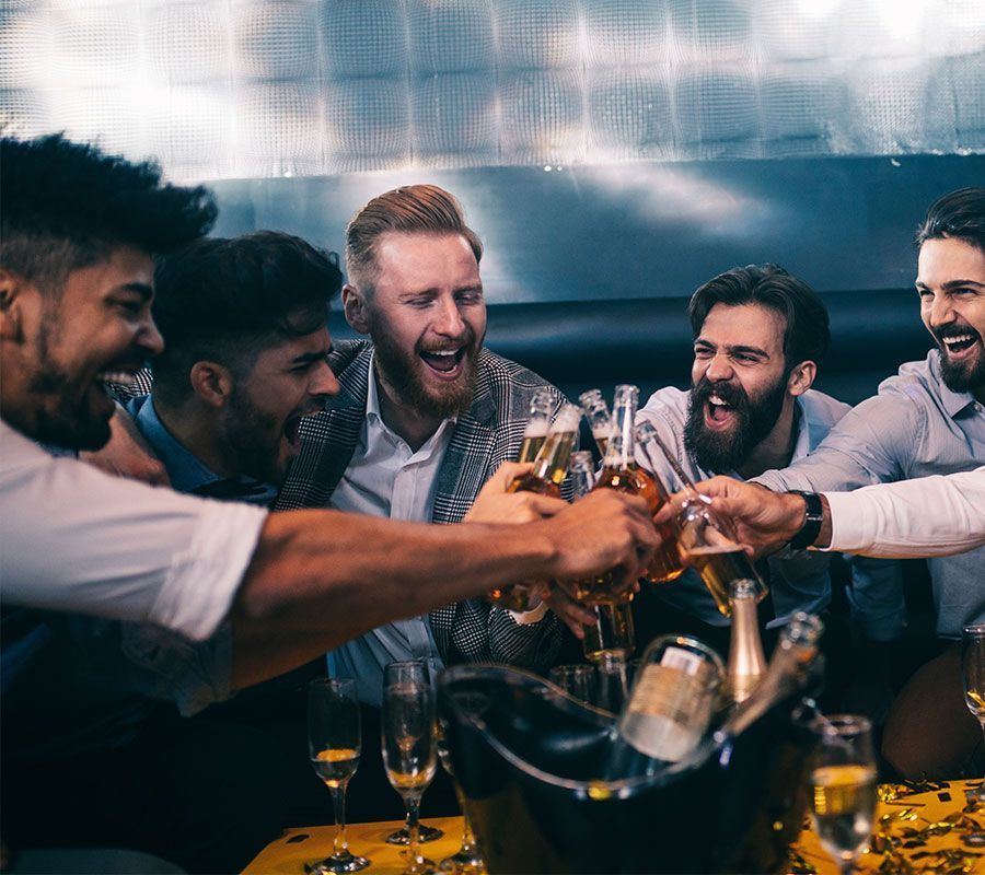 Group of men cheering with beer bottles and champagne at a bachelor party
