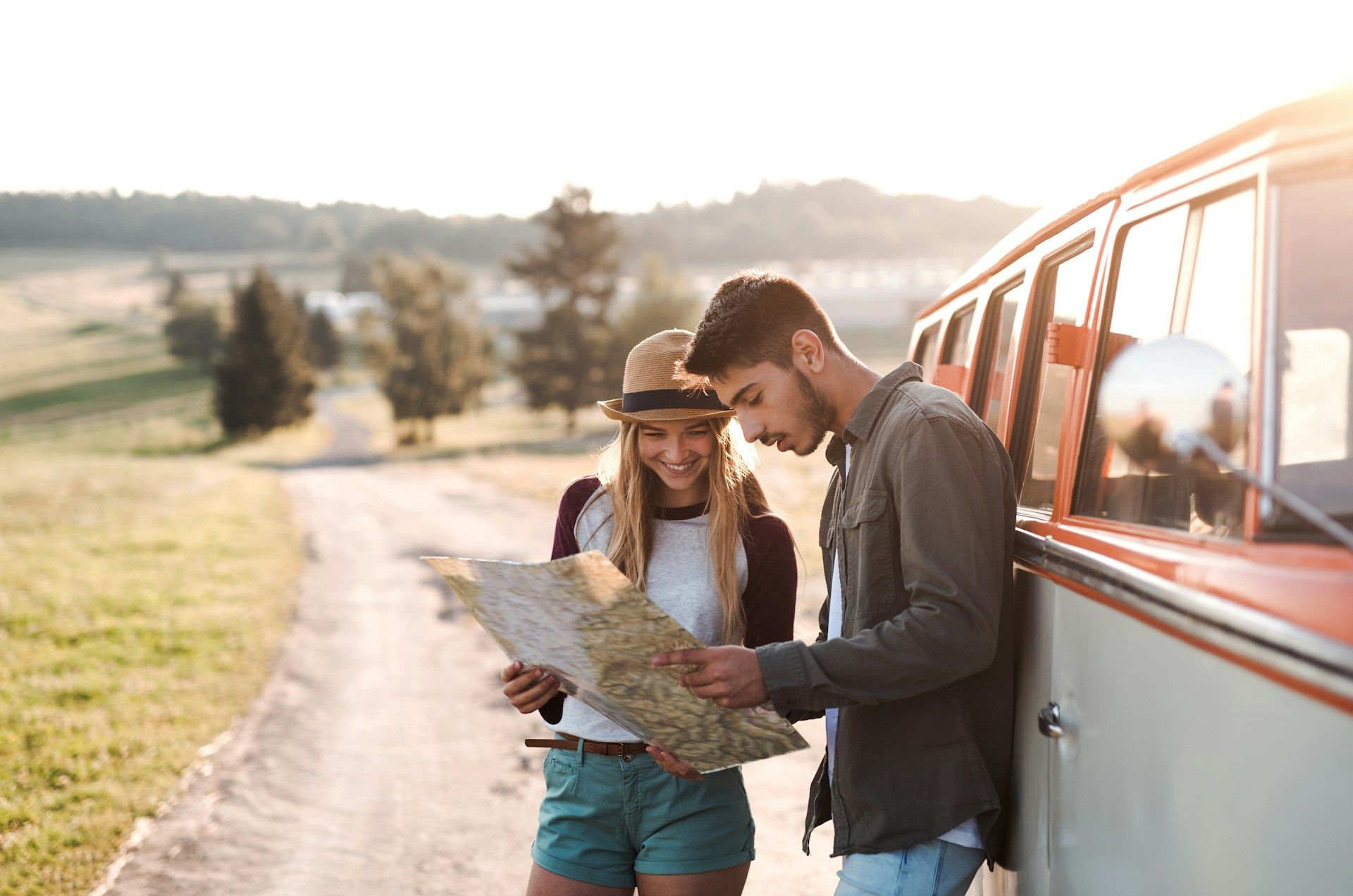 A couple looking at a map standing outside of their car