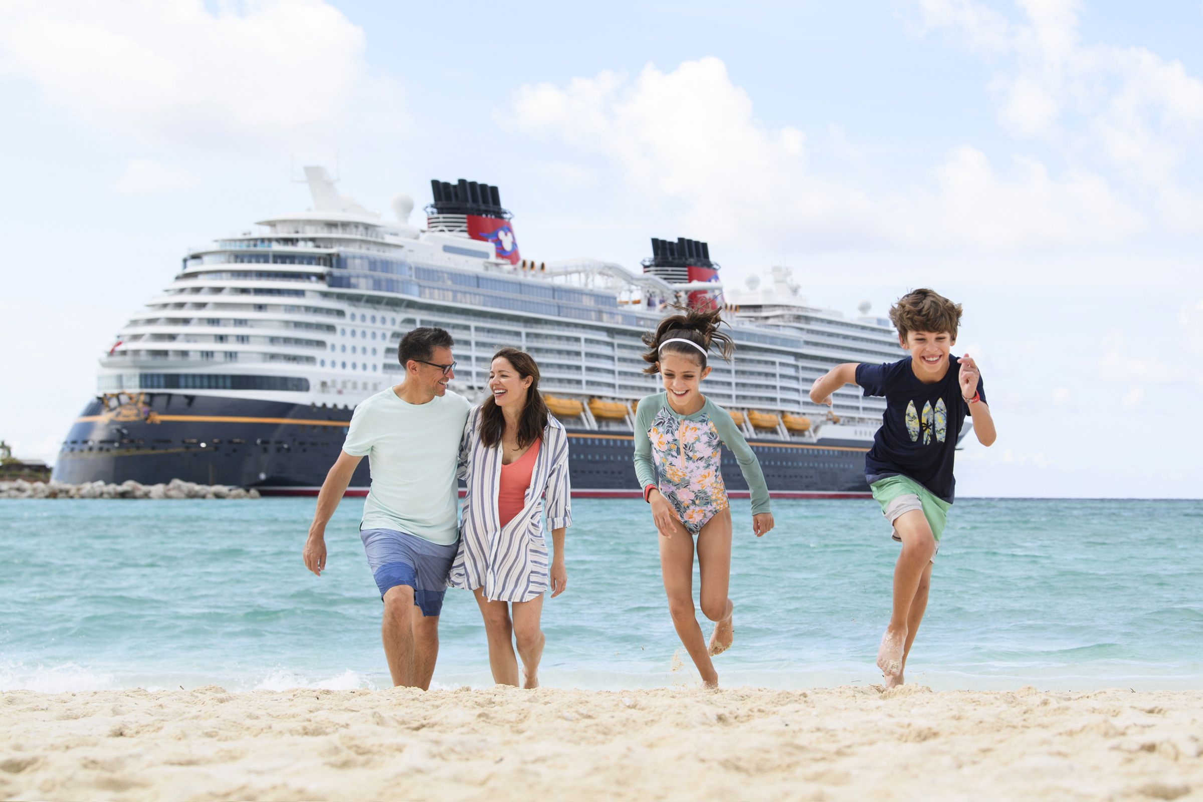 Family playing on beach with Disney cruise ship in the background