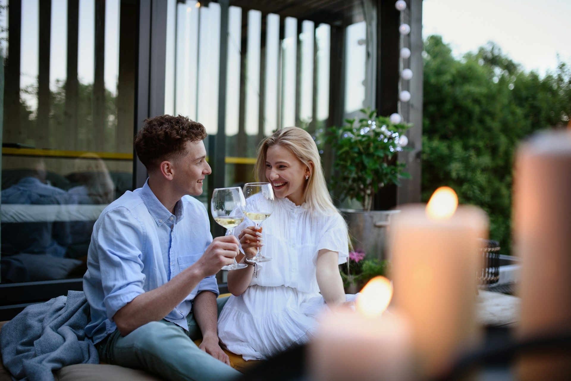 Couple clinking wine glasses while sitting outdoors in the evening.