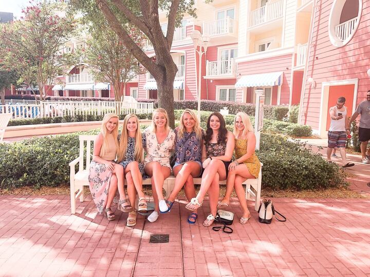 six women sitting on disney bench