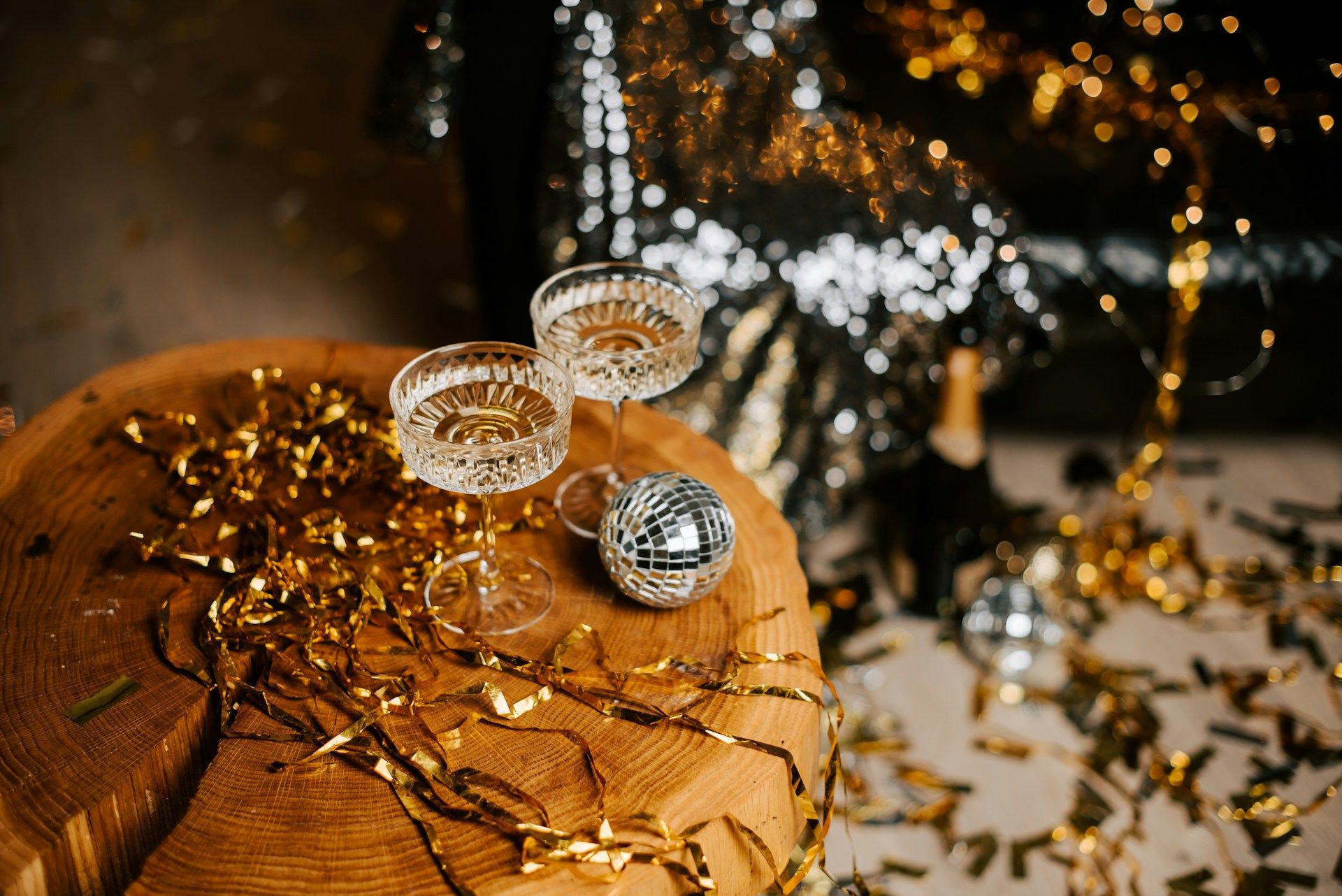 two champagne glasses sitting aside disco ball on table of golf confetti