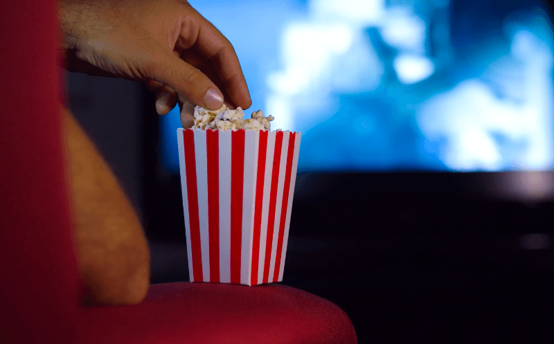 A person eating popcorn and watching a movie.
