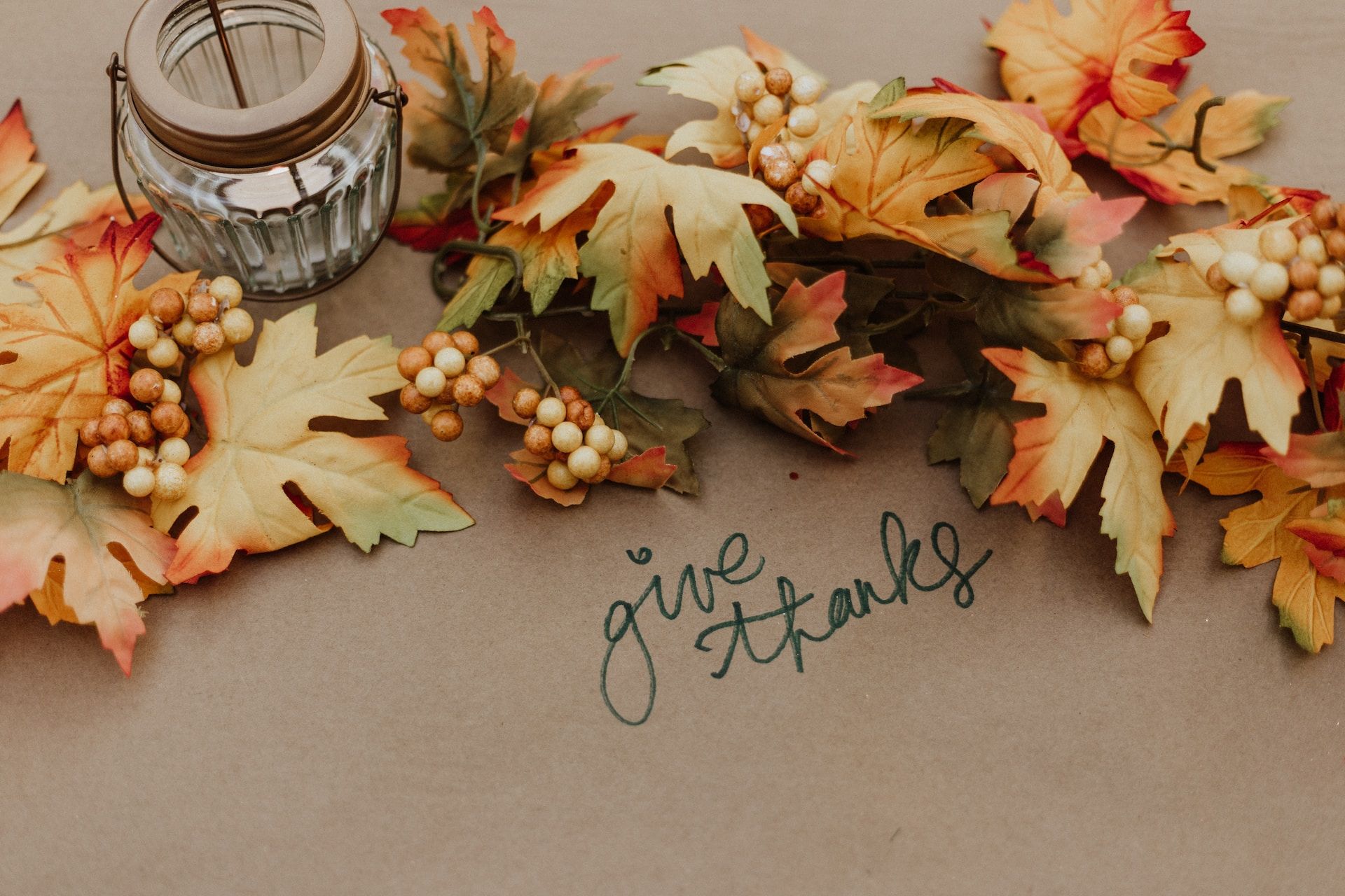candle and fall table leaves placed above the phrase give thanks written on the table