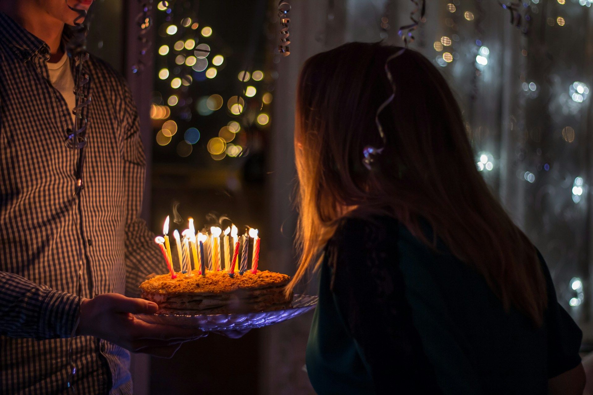 Adult birthday party moment with cake and festive lights